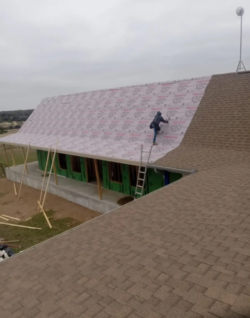 Worker preparing underlayment for a metal roof installation in Keokuk